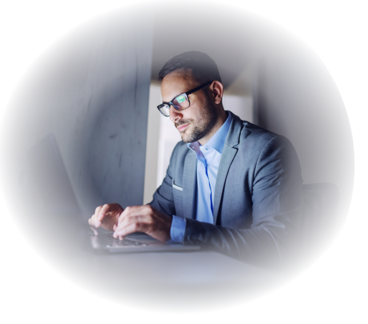 man with glasses typing on laptop