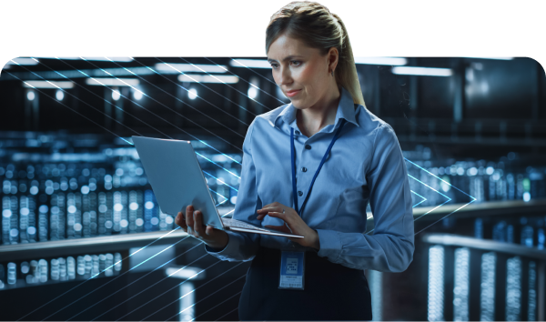 Woman in a blue shirt using a laptop in a high-tech data center with glowing blue lights and server racks in the background.